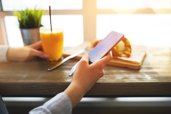 Belle femme dans un café confortable près d'une grande fenêtre assise à la table et mener la conversation sur les réseaux sociaux avec vos amis — Photo