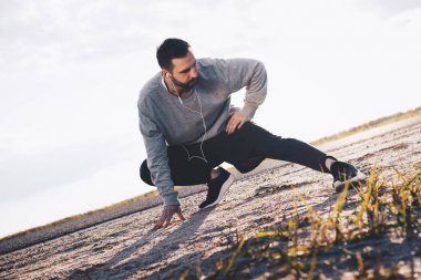 Atlet ısıtır. Oturarak ve bacaklarını esnetiyor