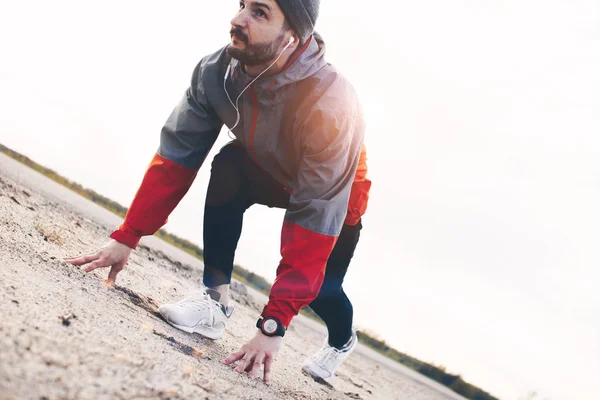 Młody silny sportowiec w słuchawki i sportowe ubrania w sneaker — Zdjęcie stockowe