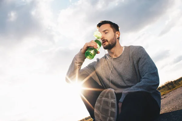 Hombre atleta sacia su sed de botella de deportes después de entrenar — Foto de Stock