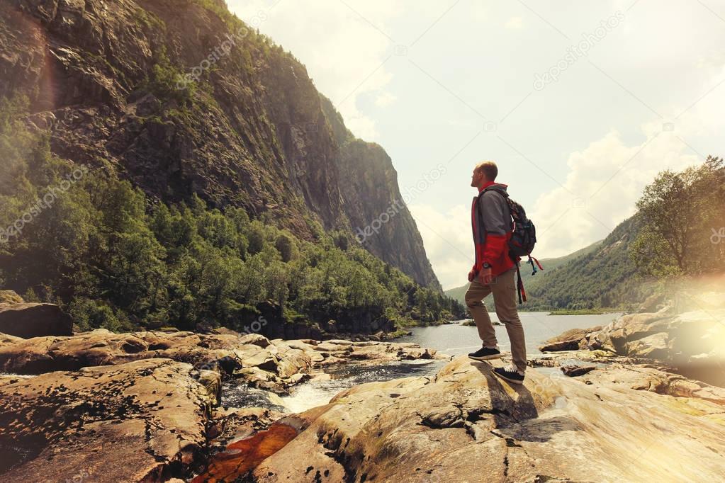 Brave and the young man standing in front of a rock in a mountain waterfall