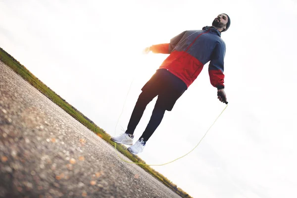 Male athlete makes a workout and jumps on the rope