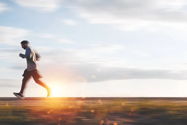 Idrottsman tränar och kör i solnedgången på utomhus i parken. Rörelseoskärpa effekt — Stockfoto