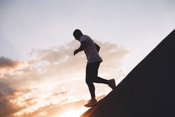 Сильний спортсмен біжить по пагорбу на заході сонця. Чоловік займається фітнесом на природі. Тренування для трейл-бігу — стокове фото