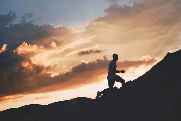 Correr a campo traviesa. Silueta de un atleta en el fondo de la hermosa puesta del sol —  Fotos de Stock