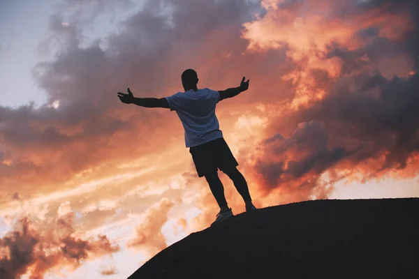 El ganador del atleta está contento con el resultado exitoso de la competición. Un atleta fuerte con las manos en alto hasta un hermoso cielo al atardecer —  Fotos de Stock