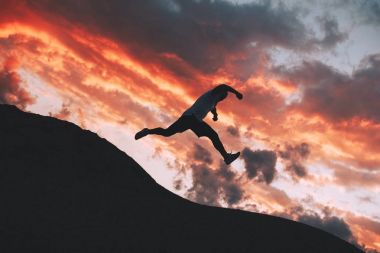 Çılgın erkek atlet düzensiz tepelerde eğitim sırasında atlama. Bir atlama şu anda güçlü bir adam silüeti