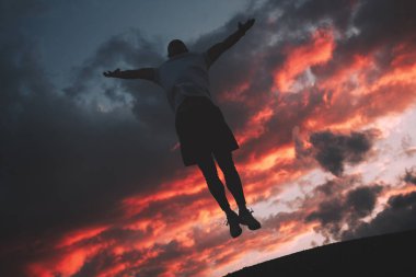 Mutlu ve başarılı bir adam gökyüzüne kadar atladı ve gün batımı gökyüzüne ellerini kaldırdı. Başarı ve zafer kavramı