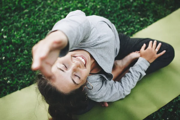 Mujer joven alegre y feliz practicando yoga en el césped verde al aire libre. Calma y relax, felicidad femenina —  Fotos de Stock