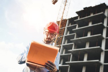 Adam mimar inşaat kask ve gözlük bina yapım aşamasında bakar. Oluşturucu ile el çizimleri