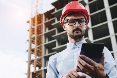 Tablet inşaat alanı üzerinde el ile güvenlik müfettişi. İşadamı Oluşturucusu endüstriyel tablet görünüyor. Kavramı mühendislik ve sanayi