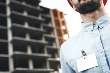 Boş beyaz boş kartı veya iş kartı rozet göğüs genç mimar veya mühendis inşaat sitenin arka planı üzerinde