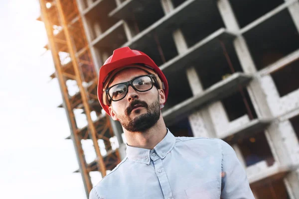 Portrait young modern bearded engineer or architect on background of building construction