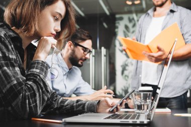Modern başlangıç yöneticilerin takım çatı alanı içinde laptop üzerinde çalışmaktadır. Ekip çalışması beyin fırtınası kavramı. Yeni fikir analiz ve planı geliştirme