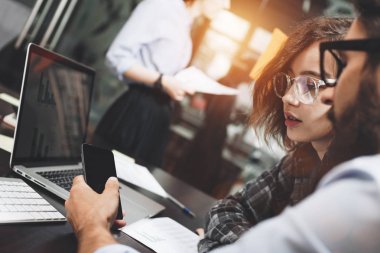 Yaratıcı iş arkadaşlarınızla Beyin fırtınası iletken modern loft alanda çalışma grubu. İş ekibi elektronik cihaz araçları kullanır. Ahşap masa üstünde genel tasarım defter. Arka plan bulanık, fişekleri