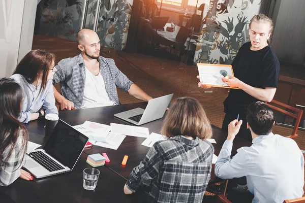 Grupo de gestores de proyectos creativos analiza el desarrollo de la startup. La gente de negocios trabaja para papeles y computadoras portátiles en el loft. Presentación del proyecto creativo — Foto de Stock