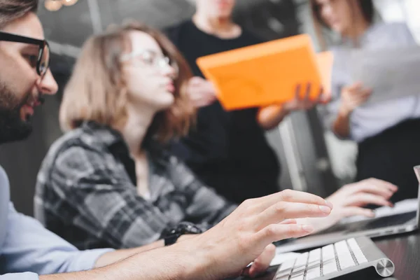 Barbă tânăr om de afaceri tastând text pe tastatura modernă. Lucru în echipă în spațiu loft. Oameni de afaceri în birou de coworking. Fundal neclară — Fotografie, imagine de stoc