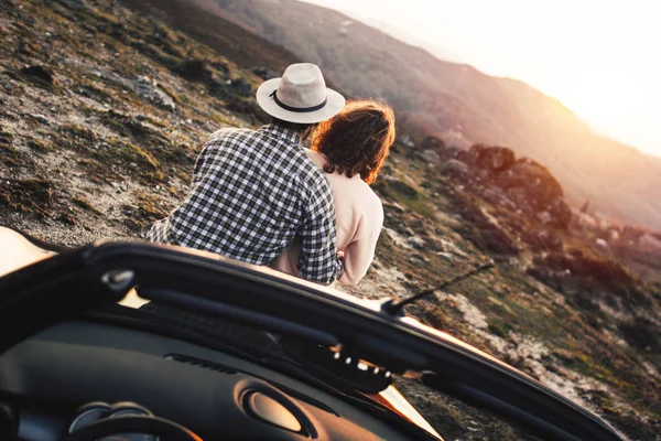 Newlyweds on a wedding trip on convertible enjoying sunset in mountains — Stock Photo, Image