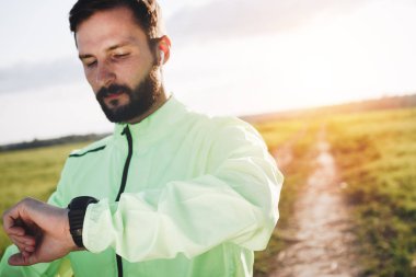 Genç atlet akıllı izleme ve çözümleme sonuçları çalıştırmak kablosuz kulaklık manzaralı sakallı