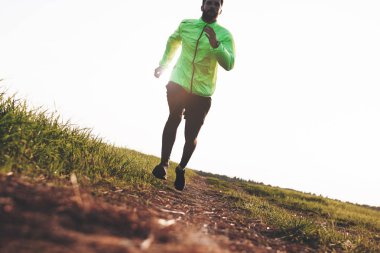 Gün batımında zor arazi üzerinde koşturup atletik adam. Spor sıkı giysi. Kasıtlı Hareket Bulanıklığı.