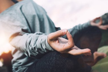 Genç kadın pratik Yoga şehir alanda çim üzerinde günbatımında. Eller meditasyon veya lotus pozisyonu kapat. Dikey, bulanık arka plan, güneş ışığı. Özgürlük kavramı