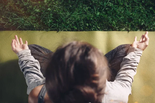 Pohled shora štíhlé mladé ženy cvičí jógu v městském parku. Dívka v lotosu představují relaxuje na zeleném trávníku po celodenní tvrdé práci. Klid a relax. Koncept svobody — Stock fotografie