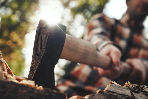 Μεγέθυνση της οξείας τσεκούρι στα χέρια ξυλοκόπος. Θολή ξυλοκόπος σε φόντο — Φωτογραφία Αρχείου