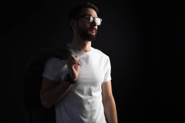 Sakallı genç hipster ceket siyah arka plan üzerine beyaz boş t-shirt ile poz gözlük