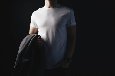 Kaslı adam elinde siyah arka plan üzerine beyaz boş tshirt ve holding ceket giyiyor