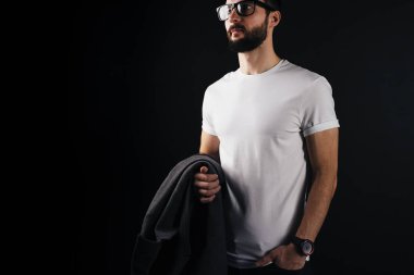 Sakallı hippi şeffaf gözlük ve boş beyaz tshirt giyiyor. Dörtte üçü siyah bir arka plan boş t-shirt elinde bir montlu adam