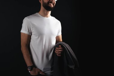 Gülümseyen bir ceket siyah bir zemin üzerine elinde tutan beyaz boş tshirt gözlük genç adam sakallı