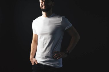 Yakışıklı sakallı hippi beyaz poz gözlük gülümseyen Studio koyu arka plan üzerinde tişört paket
