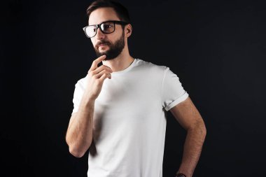Yakışıklı dalgın adam beyaz boş tshirt koyu arka planda açık gözlük sakallı. İnce gövde üzerinde boş t-shirt
