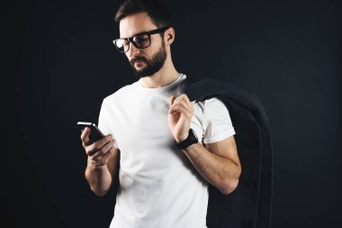 Açık gözlük ve kat boş t gömlek giymiş omuz üzerinde modern sakallı hippi. Trendy beyaz tshirt erkekte smartphone vasıl