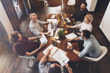 Üstten Görünüm modern ofis iş adamları vurdu. Ofis elektronik cihazlarda çalışan kadın ve erkek. Birlikte ahşap masa etrafında oturmuş bir grup genç insan çalışma