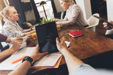 Erkek el closeup bilgisayar tablet tutarak. POV görünümü touch pad açık alan ve insanlar coworking arka plan üzerinde elinde 