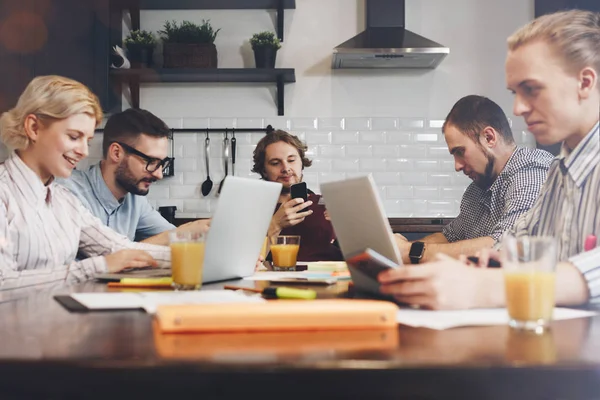 Echipa de start-up stă împreună la masă folosind laptopul din clasă. O echipă tânără de afaceri care lucrează la un nou proiect în bucătărie — Fotografie, imagine de stoc