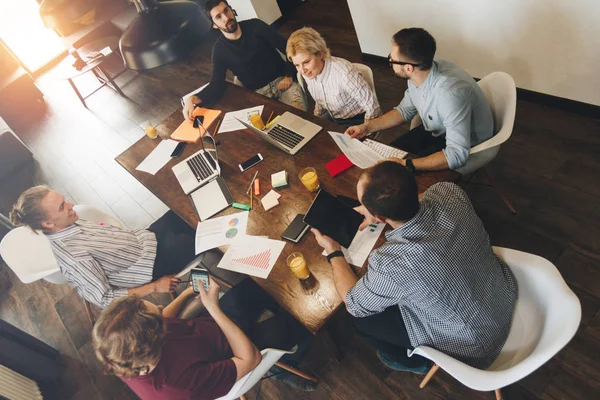 Hombre y mujer de negocios sentados alrededor de la mesa en la oficina y trabajando con computadoras portátiles y tabletas. Coworking people discutiendo nuevos negocios de desarrollo de planes — Foto de Stock