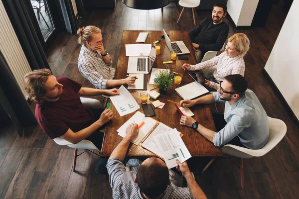 Foto på toppen av gruppen av unge næringslivsteam som samarbeider om et nytt prosjekt. Samarbeid med kreative ledere på loftsplassen. Begrepet arbeid på moderne kontor på bærbare datamaskiner og nettbrett – stockfoto