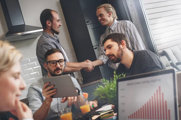 Grupo de jóvenes startups creativas están trabajando en la cocina en un nuevo proyecto. Reunirse con socios en casa y trabajar juntos en un nuevo gran negocio. Cuaderno sobre mesa de madera. Presentación de ideas, análisis de planes — Foto de Stock