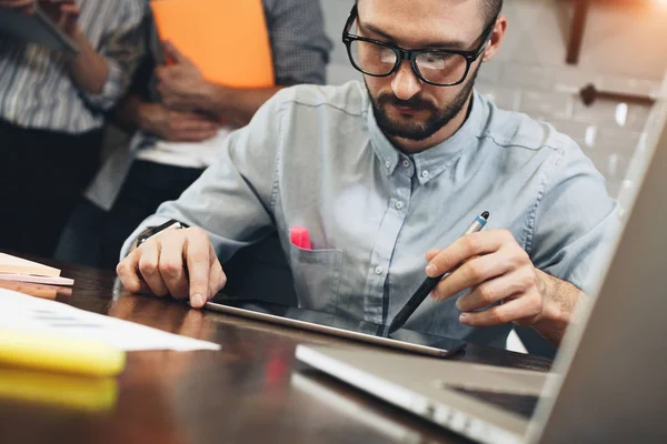 Empresario barbudo en gafas planea pasar negocios en tableta mientras está sentado en casa en la cocina. Comerciante informe de mercado de trabajo en la tableta de pantalla táctil — Foto de Stock