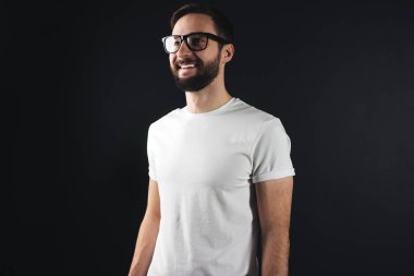 Gülerek ve gülümseyerek karanlık bir arka plan üzerinde beyaz t-shirt erkekte sakallı. Ön yüzü