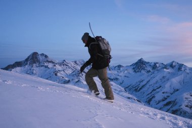 Adam explorer ile snowboard arkasından tırmanmak yüksek dağda akşam