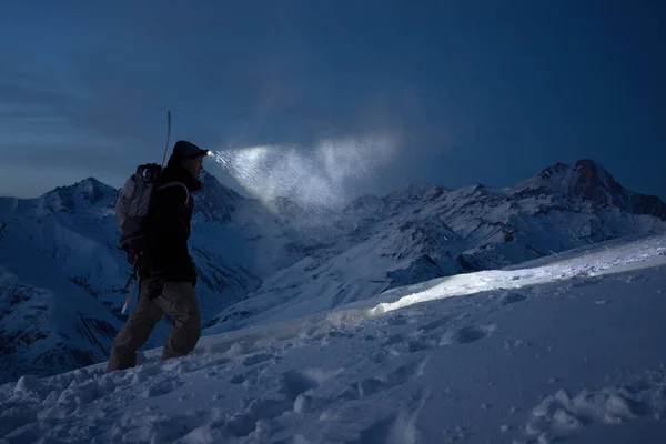 Cesur gece explorer yüksek karlı dağlardaki tırmanıyor ve yolu ile bir Far ışıkları. Aşırı seferi. Kayak turu. Snowboard tamamlama kış yamaç tırmanmaya. Backcountry
