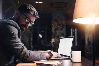 Genç proje yöneticisi laptop gece ofisinde metin yazarak. De loft alan yeni başlangıçta çalışan iş adamı sakallı. İş arkadaşınız kavramı. Parlama efekti, arka plan bulanık
