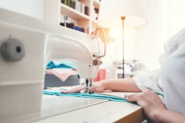 Dikiş makinesinde çalışan genç kadın terzi showroom dikmek. Terzi kumaş atölye ile çalışma. Küçük işletme