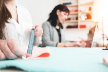 İki genç terzi kumaş Tasarım Bürosu ile çalışma. Terzi kadın bir cetvel ile kumaş parçası ölçer. Küçük işletme