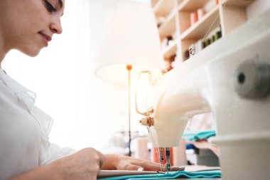 Dikiş makinesinde çalışan genç kadın terzi showroom dikmek. Terzi kumaş atölye ile çalışma. Küçük işletme