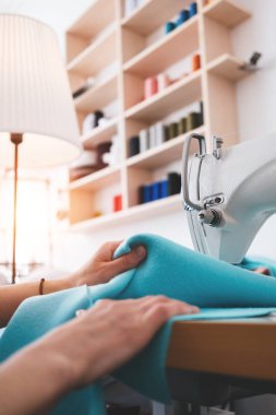 Tatlı kadın ile Studio kumaş dikiş makinesi üzerinde çalışma eller. Terzi kadın giysi Tasarım Bürosu dikiş makinesinde diker. Küçük işletme