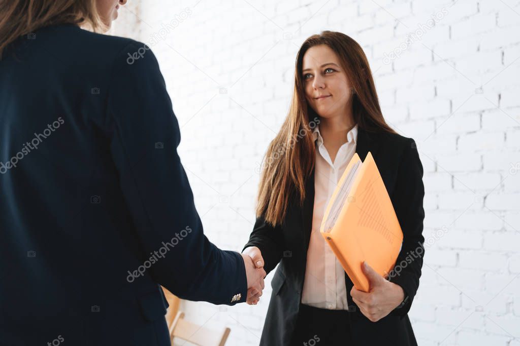 Photo of two womans handshaking process after success deal. Business female partnership handshake concept in coworking office